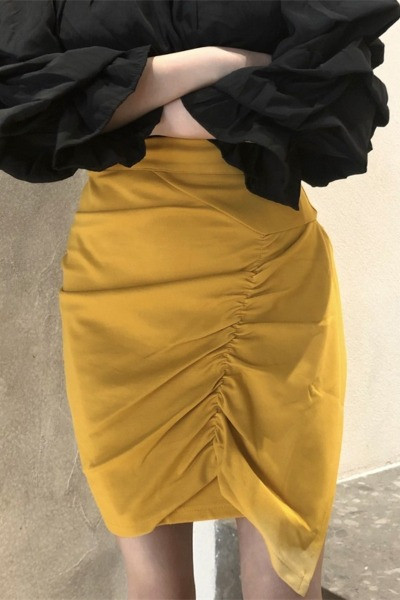 Kollane naiste asümmeetriline kõrge vöökohaga seelik, millel on volditud esiosa
