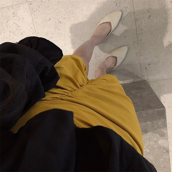 Kollane naiste asümmeetriline kõrge vöökohaga seelik, millel on volditud esiosa