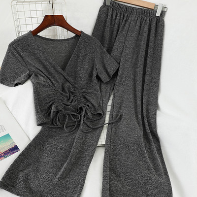 Sport-alkalmi női szett, amely egy rövid nyakkendős pólót és széles, magas derékú nadrágot tartalmaz