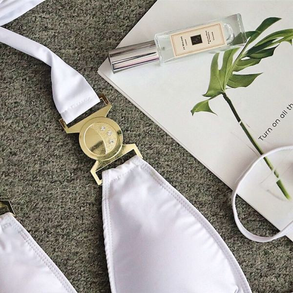 Baltas dviejų dalių maudymosi kostiumėlis su trikampiu viršumi ir metaliniais elementais