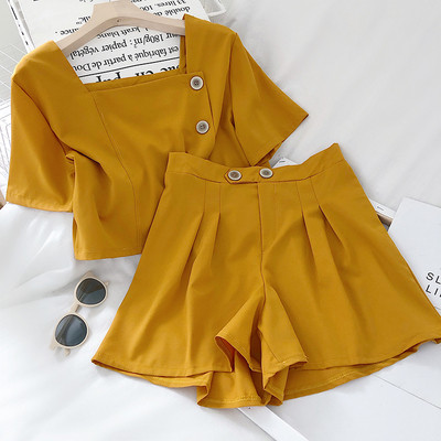 Moteriškas komplektas, kurį sudaro šortai aukštu juosmeniu ir palaidinė su sagomis