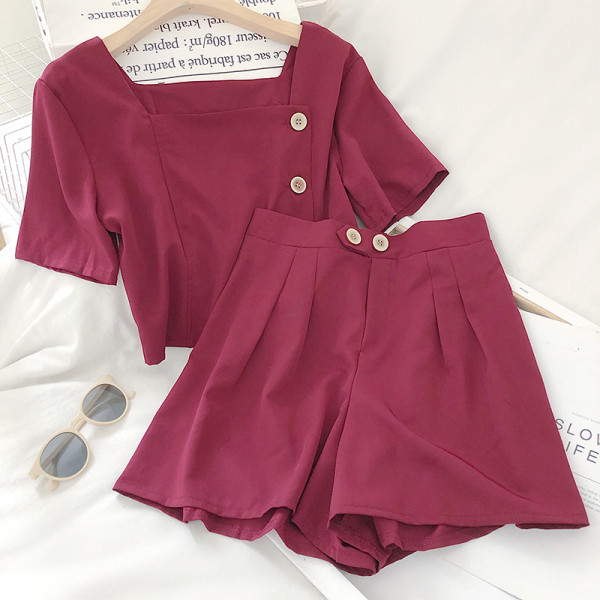 Moteriškas komplektas, kurį sudaro šortai aukštu juosmeniu ir palaidinė su sagomis