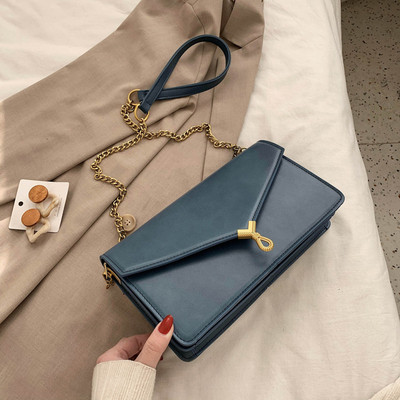 Moderni moteriška rankinė su metaliniu užsegimu ir ilga rankena