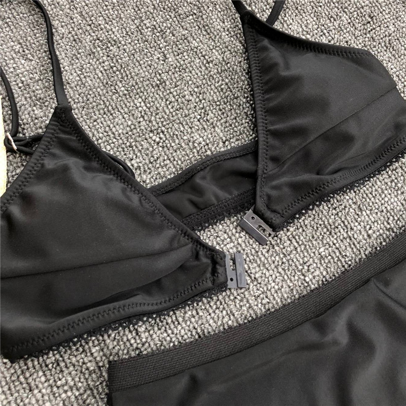 Mūsdienīgs melns divdaļīgs peldkostīms ar trīsstūrveida augšdaļu un augstu vidukli