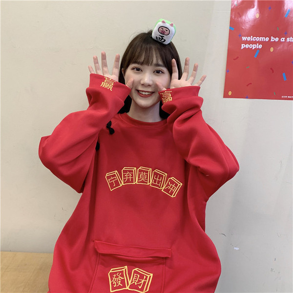 Széles női pulóver zsebbel és hímzéssel