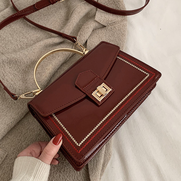 Stilingas moteriškas lakuotos odos krepšys su metaliniu užsegimu ir trumpa bei ilga rankena