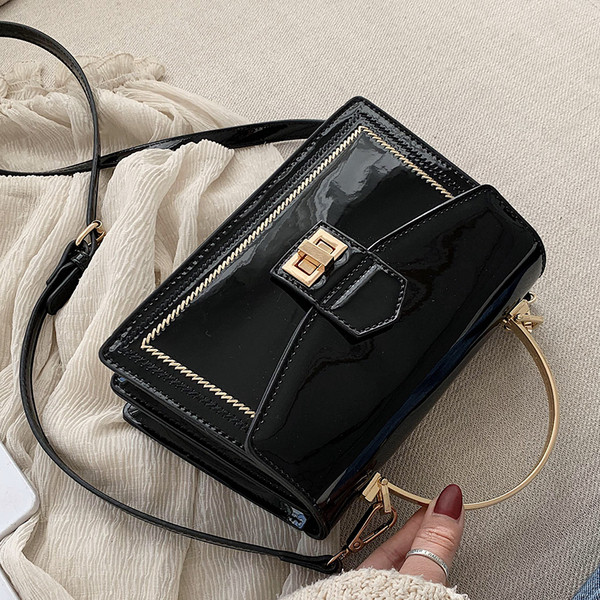 Stilingas moteriškas lakuotos odos krepšys su metaliniu užsegimu ir trumpa bei ilga rankena