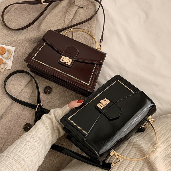 Stilingas moteriškas lakuotos odos krepšys su metaliniu užsegimu ir trumpa bei ilga rankena