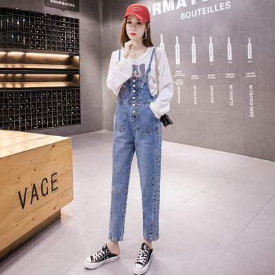 Įprastas džinsinis moteriškas kombinezonas su plonais petnešėlėmis ir mėlynos spalvos sagomis