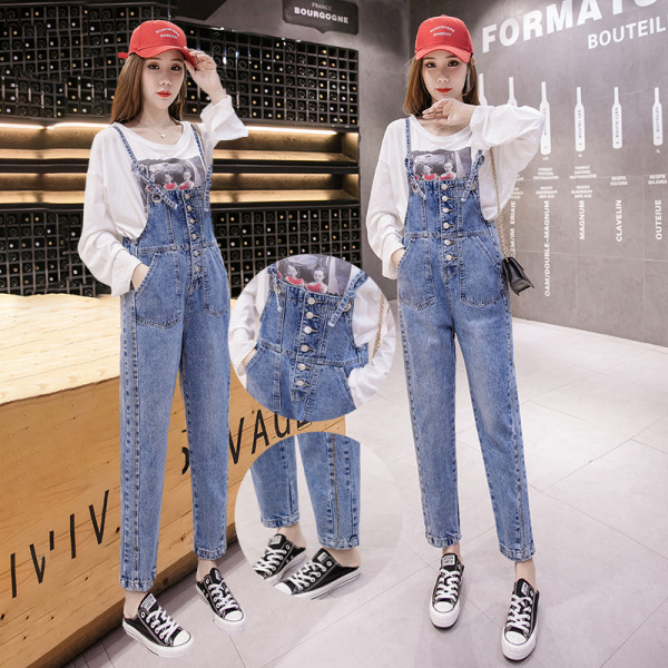 Įprastas džinsinis moteriškas kombinezonas su plonais petnešėlėmis ir mėlynos spalvos sagomis