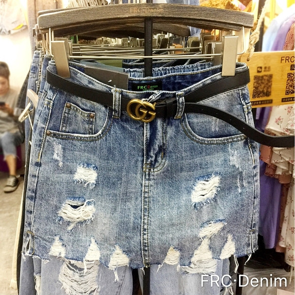 Modern női farmerszoknya szakadt motívumokkal, magas derékkal