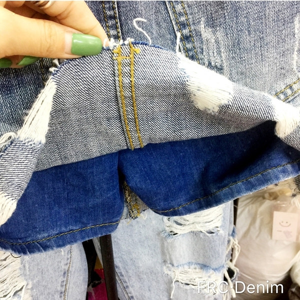 Modern női farmerszoknya szakadt motívumokkal, magas derékkal