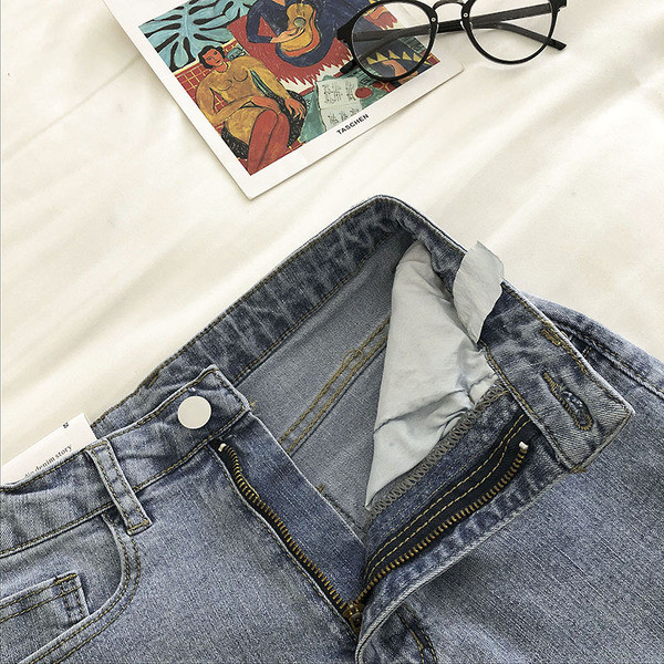 Elastīgi īsi džinsi ar kabatām un saplēstiem motīviem