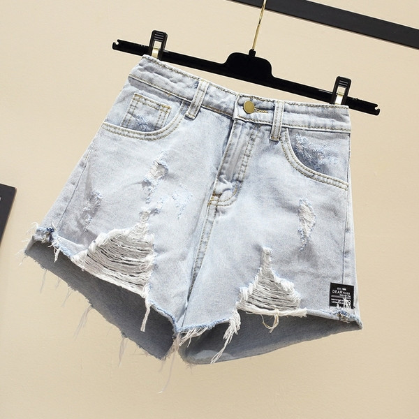 Naiste lühikesed teksad embleemi ja rebenenud motiividega