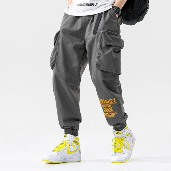 Modernas vīriešu bikses ar lielām kabatām un uzrakstu