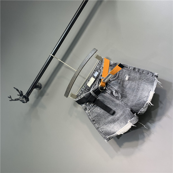 Modern női rövid farmernadrág övvel, szakadt motívumokkal