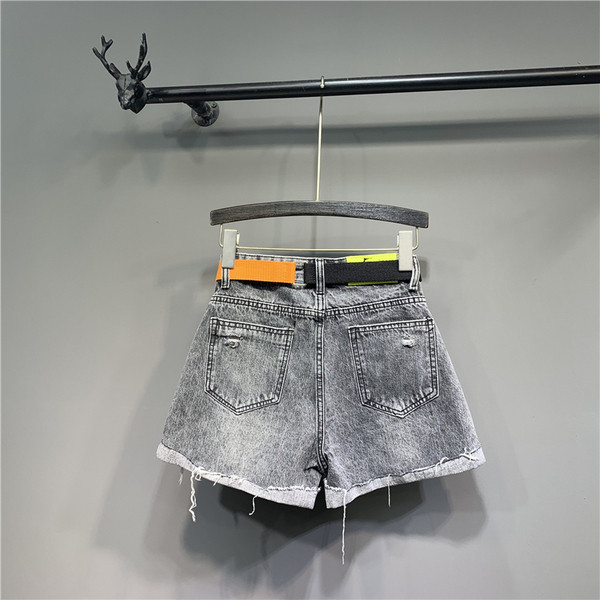 Modern női rövid farmernadrág övvel, szakadt motívumokkal