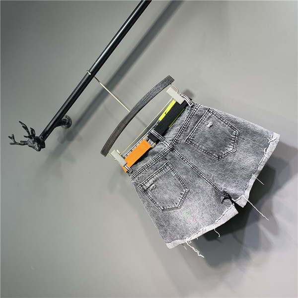 Modern női rövid farmernadrág övvel, szakadt motívumokkal