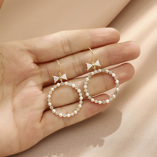 Egyszerű női kerek fülbevaló gyöngyökkel és szalaggal