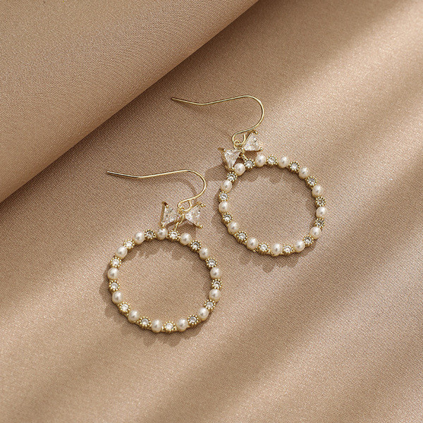 Egyszerű női kerek fülbevaló gyöngyökkel és szalaggal