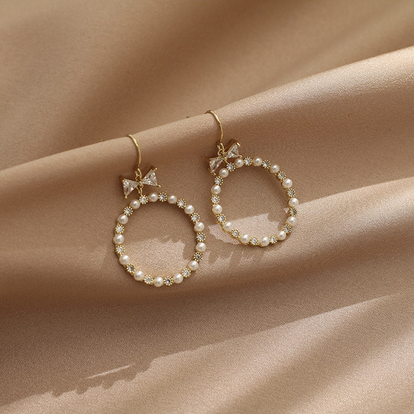 Egyszerű női kerek fülbevaló gyöngyökkel és szalaggal