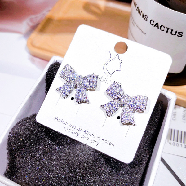 Moderni sieviešu auskari lentes formā, kas apvilkta ar akmeņiem