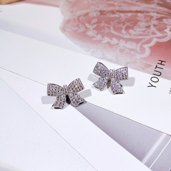 Moderni sieviešu auskari lentes formā, kas apvilkta ar akmeņiem