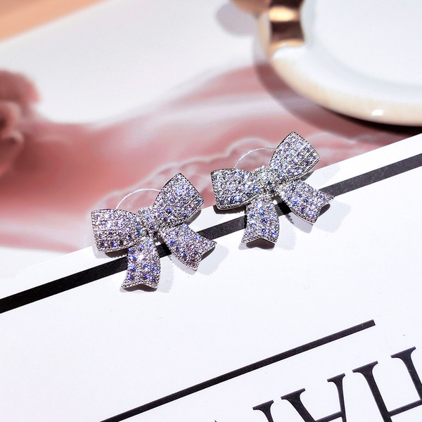 Moderni sieviešu auskari lentes formā, kas apvilkta ar akmeņiem