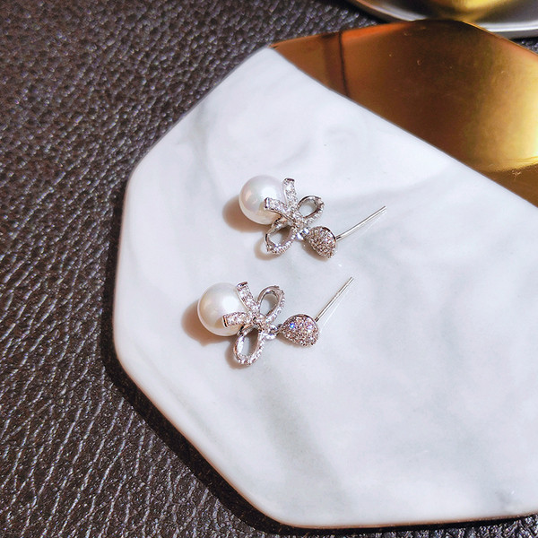 Vienkārši sieviešu auskari ar pērli un lenti ar akmeņiem