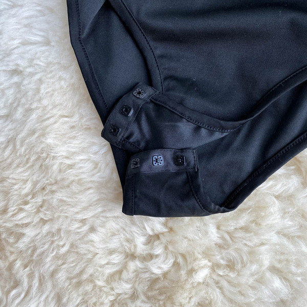 Hétköznapi női test, csupasz váll és hosszú ujjú fekete színben