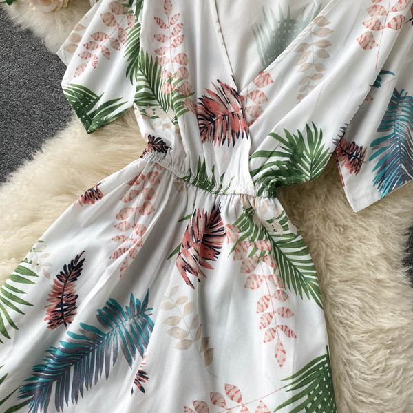 Balts sieviešu kombinezons ar ziedu apdruku un špica kakla izgriezumu