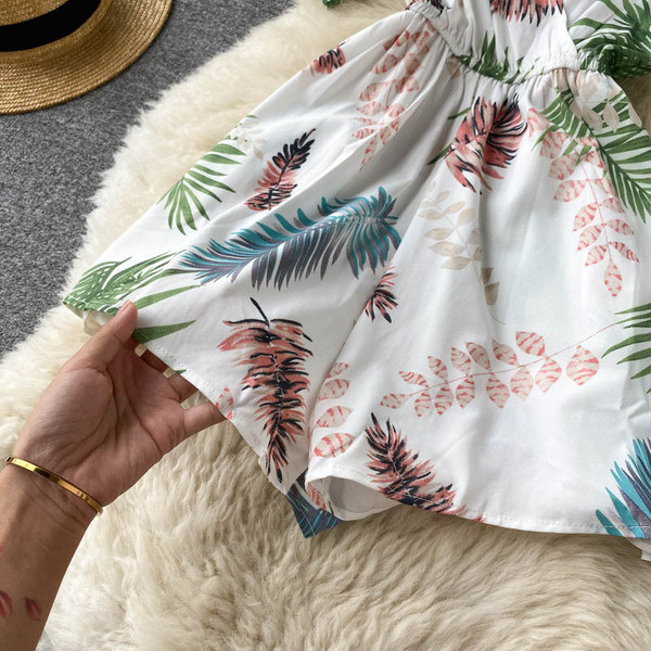 Balts sieviešu kombinezons ar ziedu apdruku un špica kakla izgriezumu